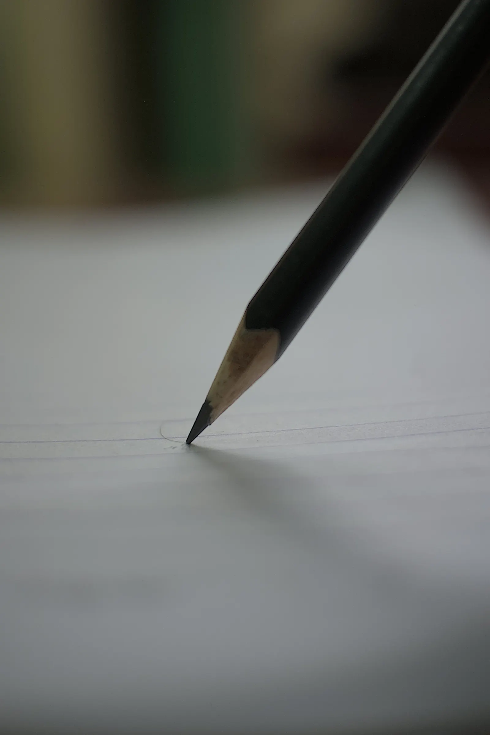 Gros plan sur la pointe d'un crayon à papier noir posé sur une feuille blanche