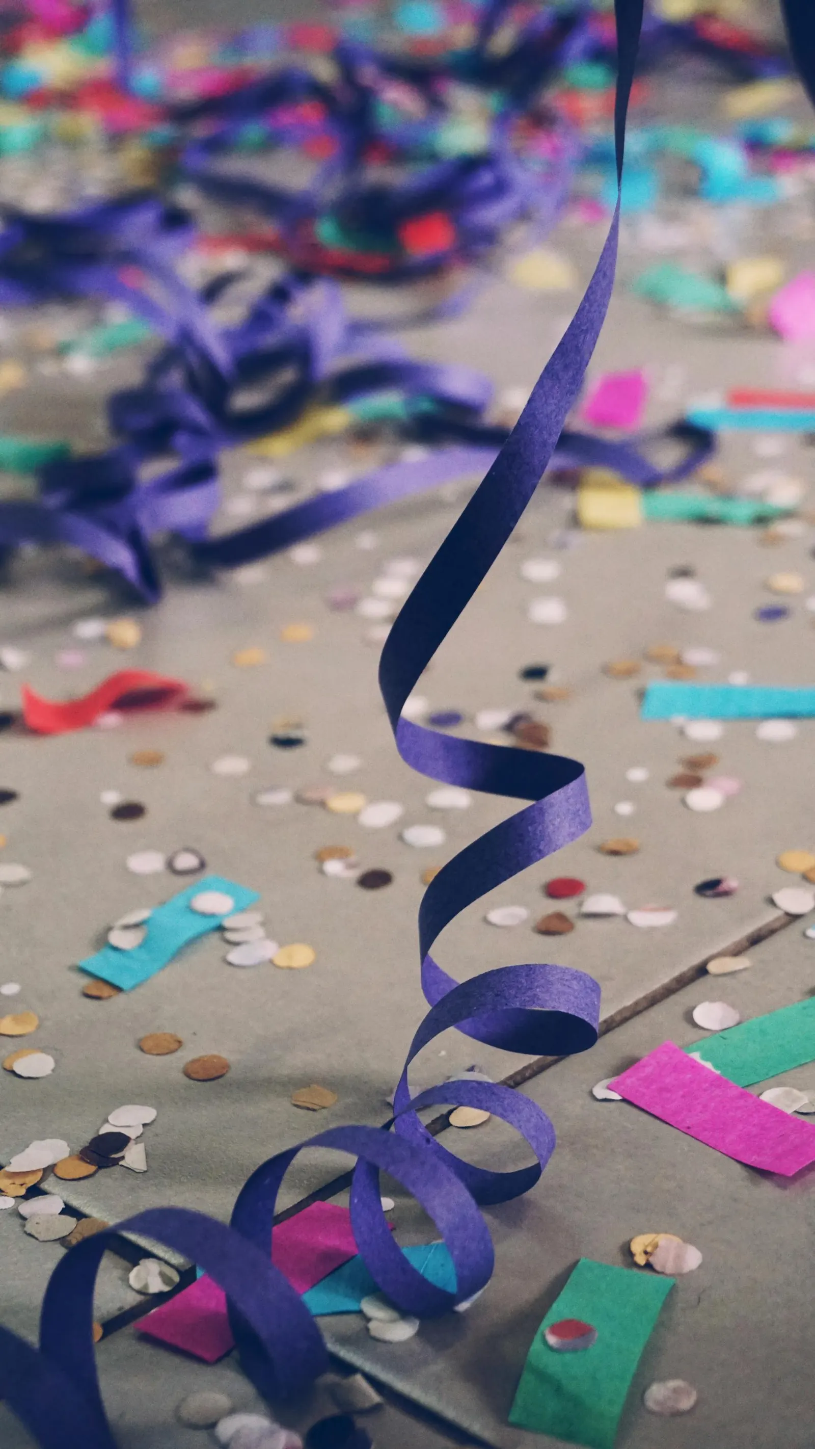 Confettis de toutes les couleurs et serpentin violet sur le sol après une fête